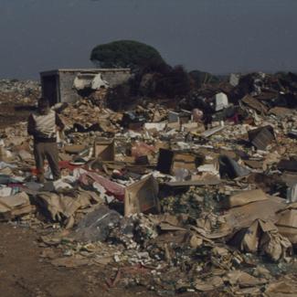Pored bora u betonskim blokovima pod plažom kućica; u I. planu čovjek prebire po smeću; Gradski deponij