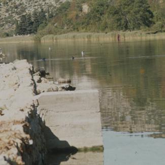 Kraj pristupa rijeci s lijeve obale u Obrovcu; galebovi na rijeci ispod tvornice 